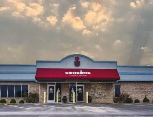 A building with a maroon awning and clouds in the sky.