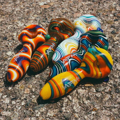 Five colorful, swirl-patterned glass pipes arranged on a textured surface.