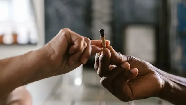 A close up of 2 hands. One hand is passing a joint to the other person's hand. 
