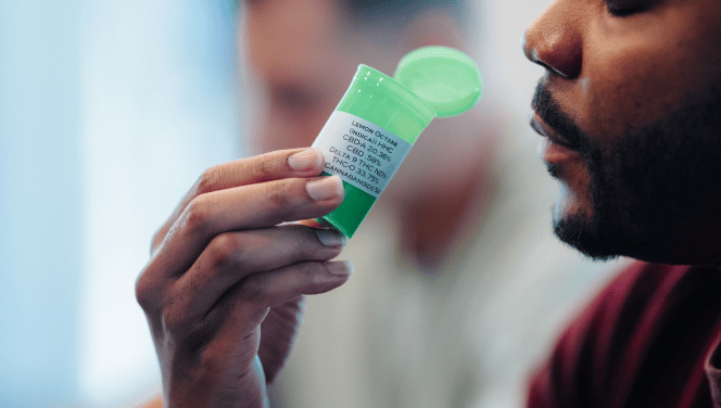 An Illinos cannabis patient smells the marijuana from the labled green bottle with childproof lid. 